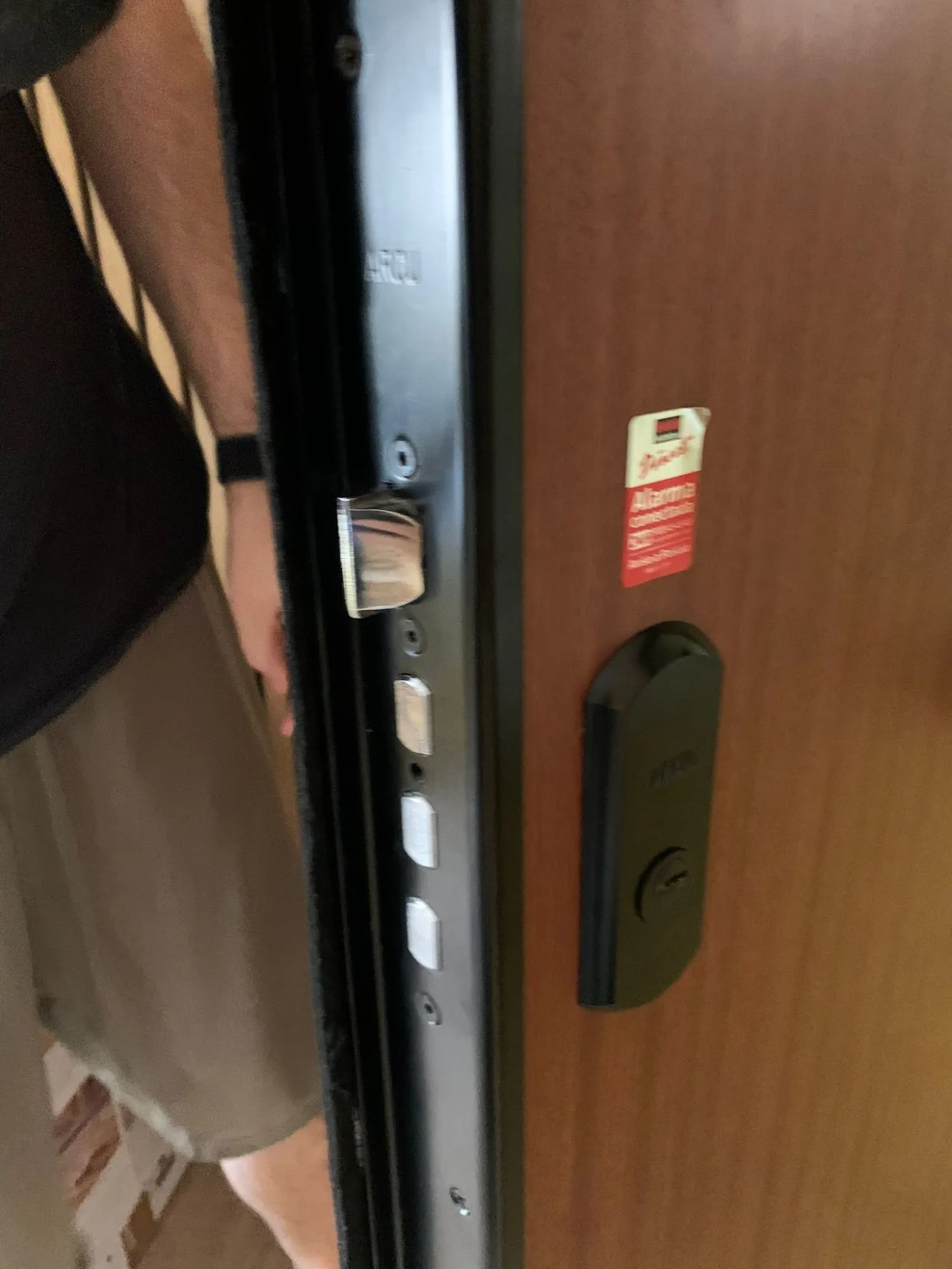 Puerta blindada abierta en Las Rozas, con el frontal de la cerradura multipunto, sus bulones y el escudo protector negro del bombín.
